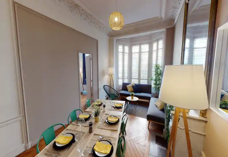 Espace de vie lumineux et soigné avec une table dressée pour dîner et un coin salon confortable près de larges baies vitrées — idéal pour recevoir et se détendre.