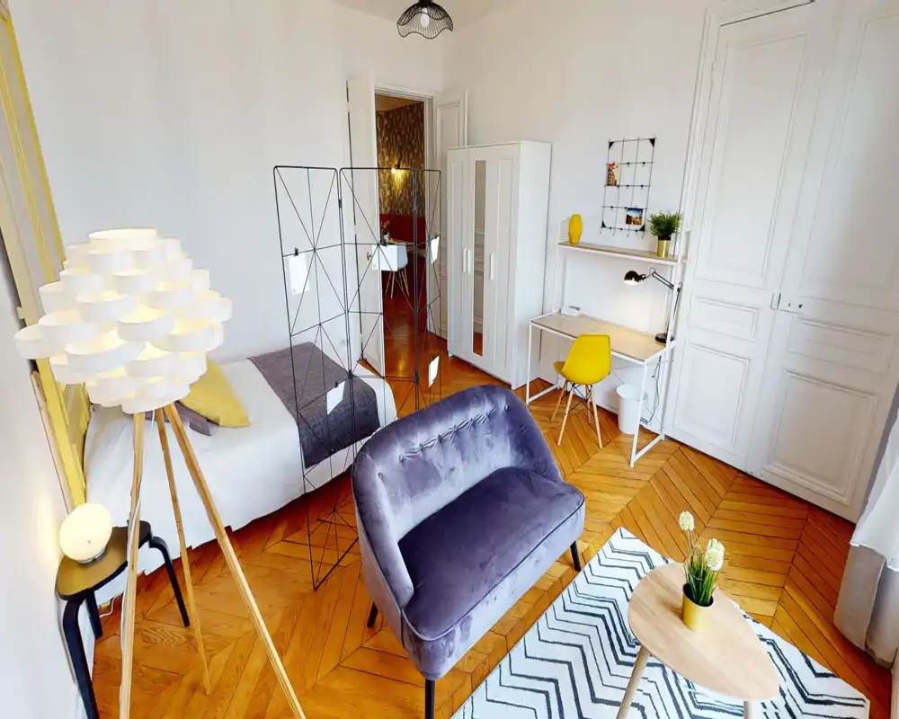Camera da letto luminosa e di design con letto singolo, divanetto in velluto, parquet e scrivania con sedia gialla — perfetta per un soggiorno cittadino confortevole.