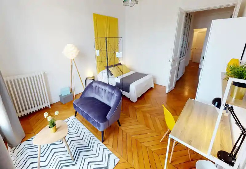 Bright, stylish bedroom with a double bed, decorative room divider and a cozy seating area with a velvet loveseat and coffee table.