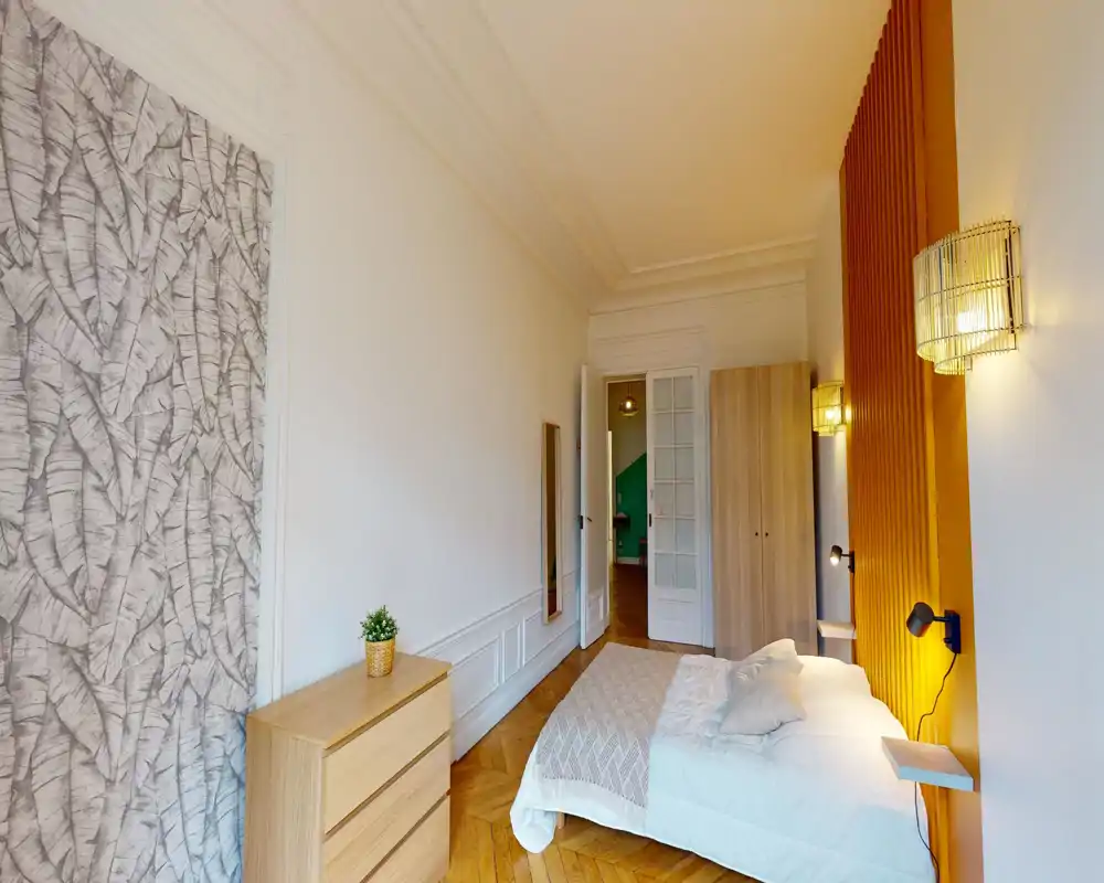 Chambre lumineuse et moderne avec un lit double confortable contre un mur d'accent chaud, lampes de chevet et parquet — idéale pour un séjour cosy.