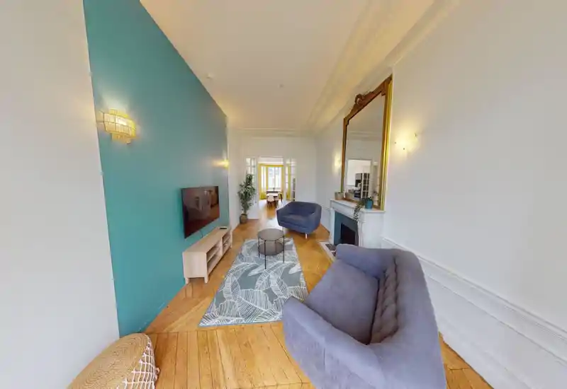 Salon spacieux et élégant avec un mur d'accent bleu-vert, canapés confortables, tapis décoratif et grand miroir au-dessus de la cheminée — espace lumineux et accueillant.