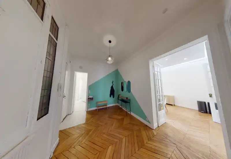 Entrée lumineuse et élégante avec parquet en chevrons, mur d'accent peint, patères et petite console — espace d'accueil accueillant et lumineux.