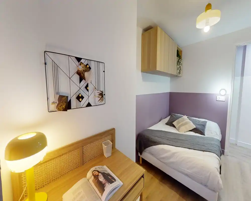 Dormitorio doble acogedor con cama bien tendida, lámpara de mesilla cálida, escritorio de madera y detalles decorativos suaves: bien iluminado y decorado con buen gusto para una estancia cómoda.