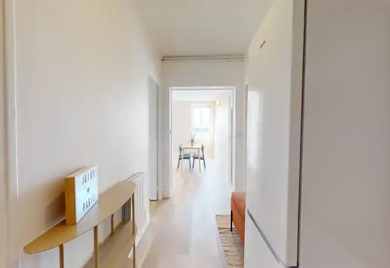 Entrée lumineuse et minimaliste avec parquet clair, une fine console et vue sur la salle à manger ; murs blancs et lumière naturelle pour une impression d'espace.