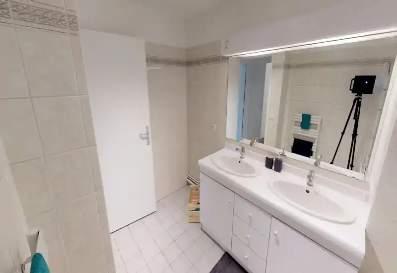 Bright, modern bathroom with a double sink vanity, large mirror and tiled walls. Clean white fixtures and good lighting create a fresh, functional space.
