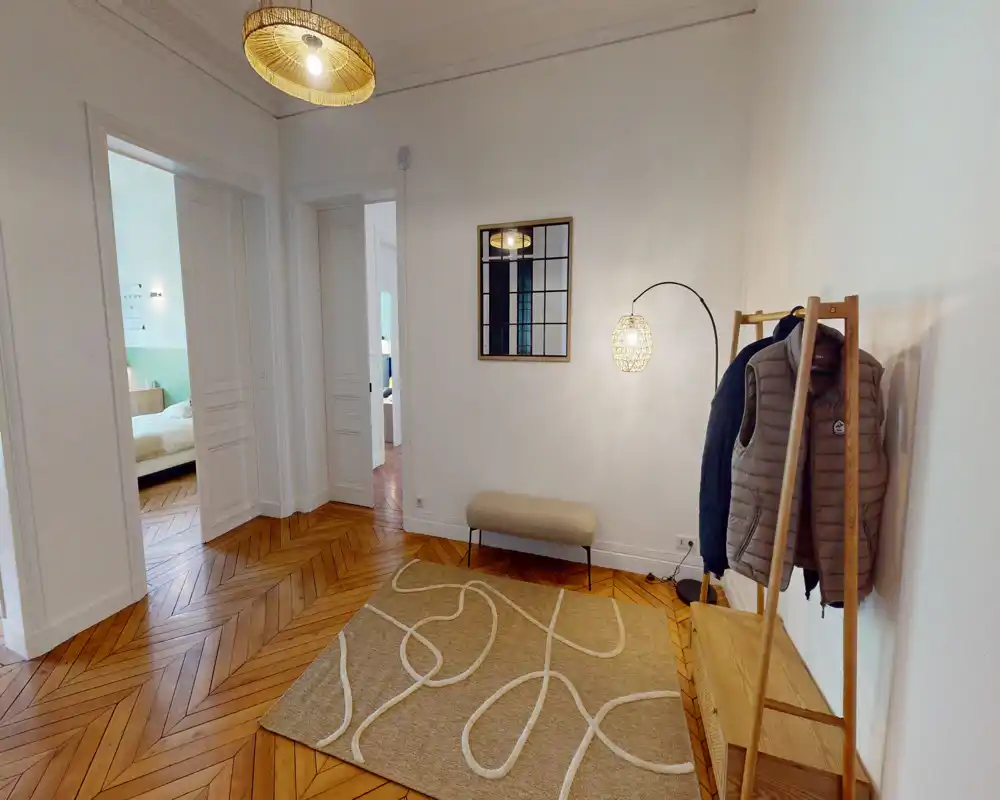 Entrée lumineuse et accueillante avec parquet en chevrons, banc, portemanteau et suspension décorative — idéale pour une bonne première impression.