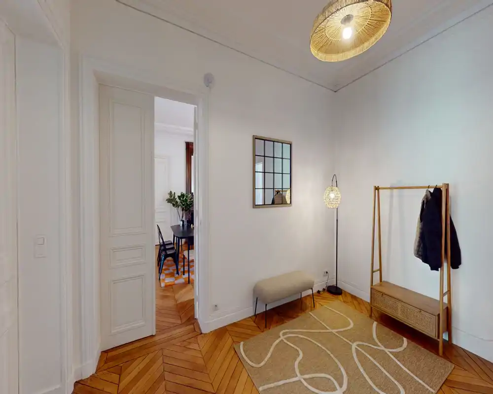 Entrée lumineuse et élégante avec parquet, banc, porte-manteau et éclairage décoratif — un hall accueillant qui mène à la salle à manger.