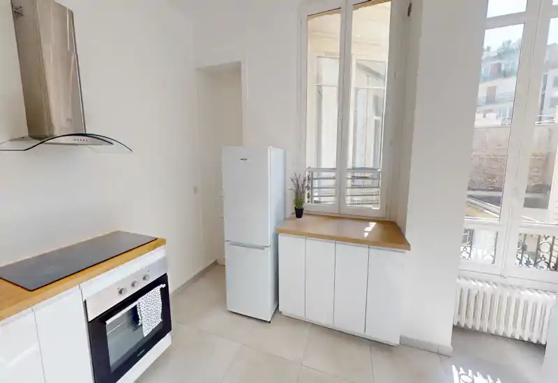 Bright modern kitchen with white cabinets, wooden countertops, built-in oven and large windows that provide abundant natural light.