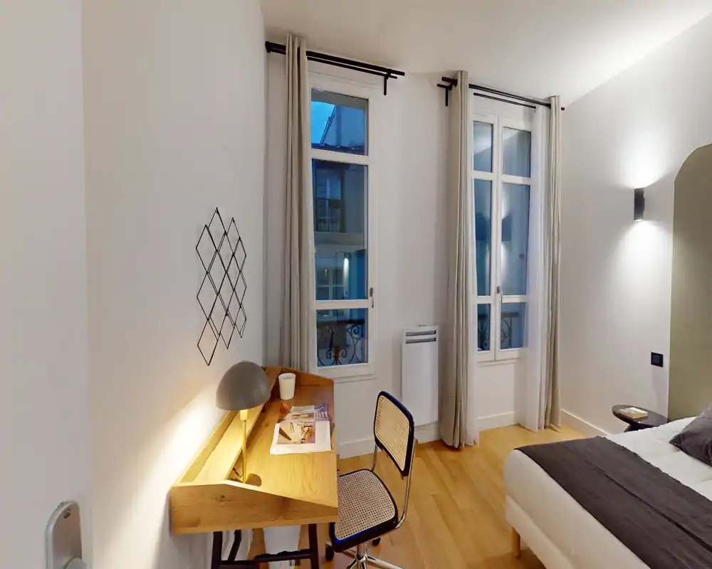Chambre lumineuse et moderne avec un lit double confortable, parquet et un petit bureau près de la fenêtre — parfaite pour travailler ou se détendre.