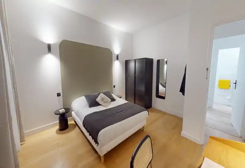 Chambre moderne et lumineuse avec un lit double bien fait, textiles doux et parquet chaleureux ; une grande armoire et un miroir pleine longueur complètent l'espace.