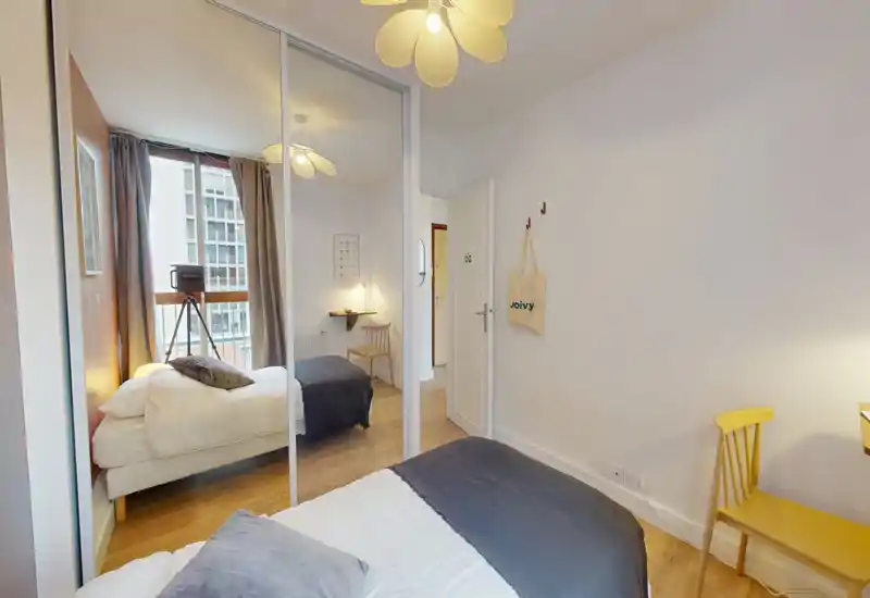 Bright, modern bedroom with a comfortable double bed, mirrored wardrobe that adds depth, soft textiles and a small desk by the window.