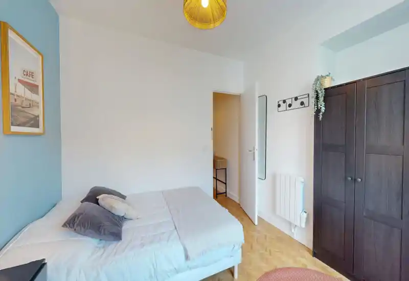 Chambre lumineuse et soignée avec un confortable lit double, des coussins douillets et une armoire indépendante; mur d'accent bleu et parquet chaleureux apportent une ambiance cosy.