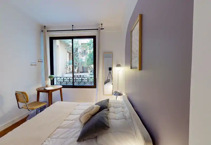 Chambre lumineuse et soignée avec un grand lit, une literie moelleuse, coussins, lampe de chevet et fenêtre donnant sur de la verdure — idéale pour une annonce chaleureuse.