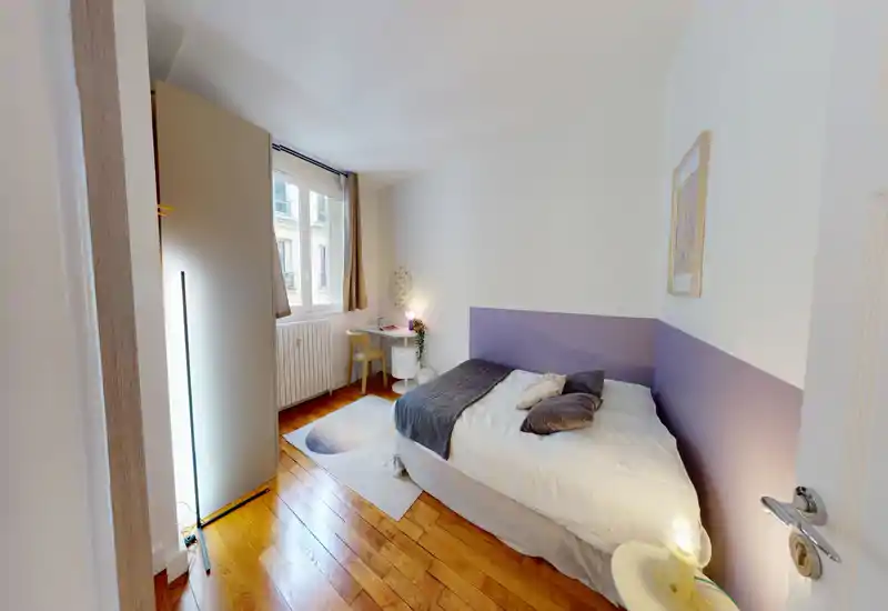 Chambre lumineuse et bien décorée avec un lit double, linge de lit doux, lampes de chevet et un petit bureau près de la fenêtre — idéale pour se reposer et travailler légèrement.