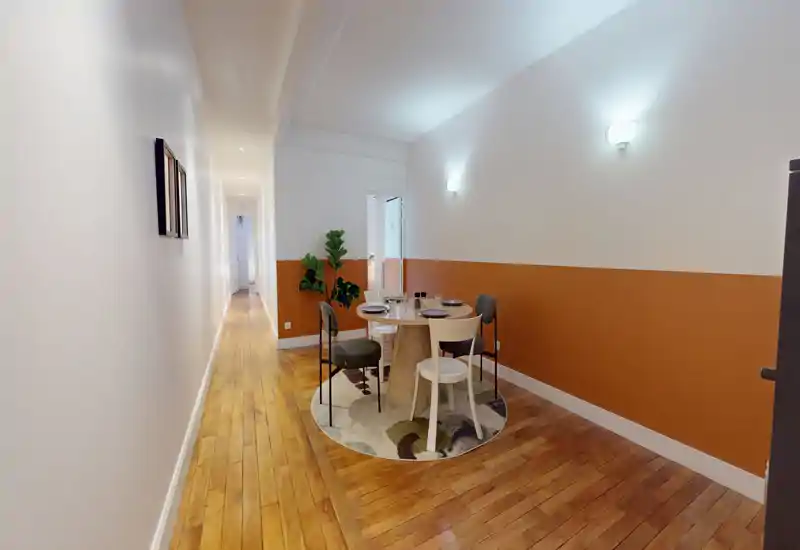 Coin repas chaleureux avec table ronde pour quatre, mur bi‑ton chaud et parquet en bois. Le tapis et les plantes donnent une atmosphère accueillante, idéale pour les petits appartements urbains.