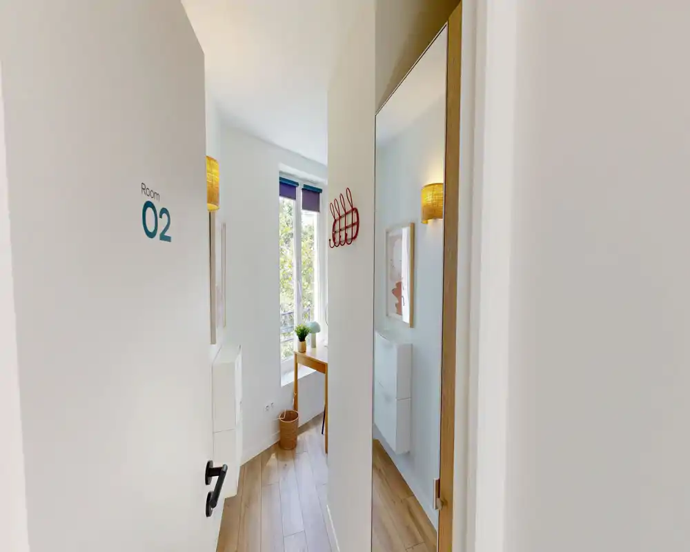 Entrée lumineuse et étroite avec miroir pleine hauteur, patères murales et lumière naturelle provenant d'une fenêtre : style minimal et soigné, parfait pour petits appartements.