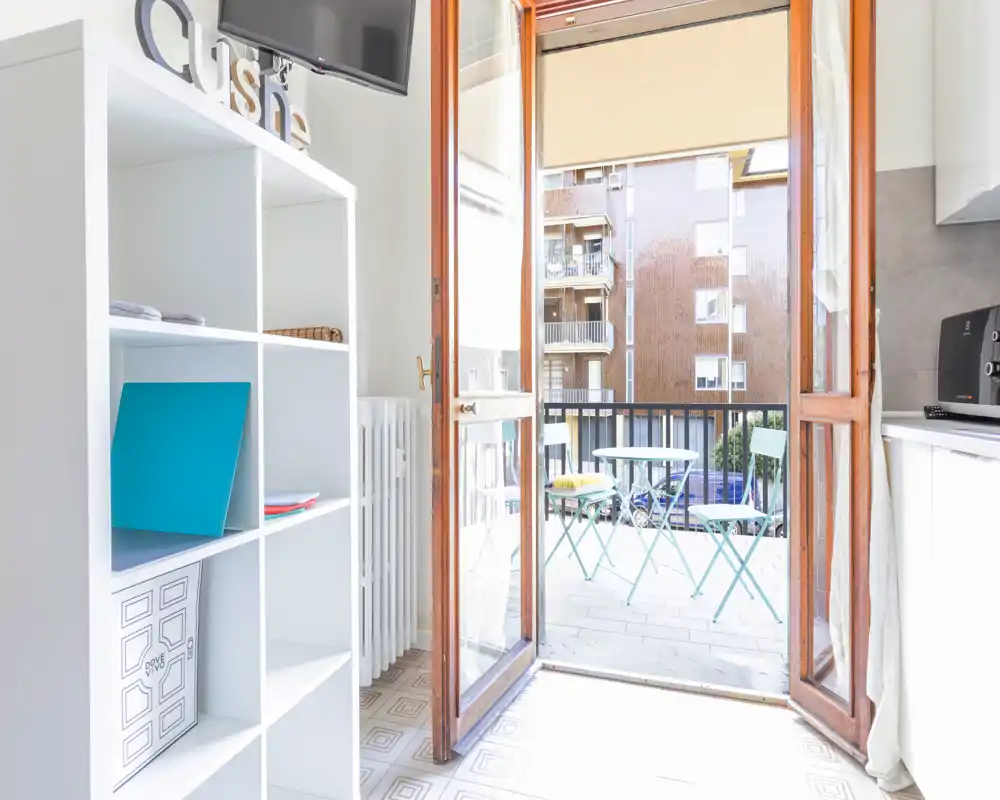 Piccolo balcone soleggiato con tavolino e sedie pieghevoli, accessibile dalla zona giorno — perfetto per un caffè mattutino con vista sulla città.