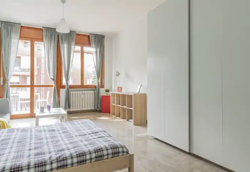 Bright, modern bedroom with a wooden bed, large windows and sheer curtains letting in plenty of natural light. Minimal, Scandinavian-style storage and a polished floor create a fresh, airy atmosphere ideal for listings.