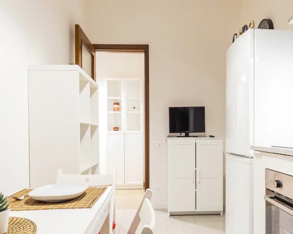 Bright, compact kitchen area with a small dining table, white cabinets and modern appliances—ideal for a cozy city apartment.