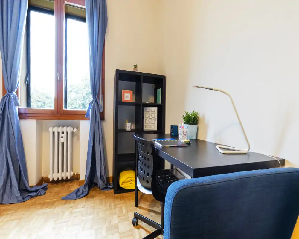 Espace de travail lumineux et soigné dans un coin de la pièce avec bureau, chaise, étagère cubique et grande fenêtre avec rideaux apportant la lumière naturelle.