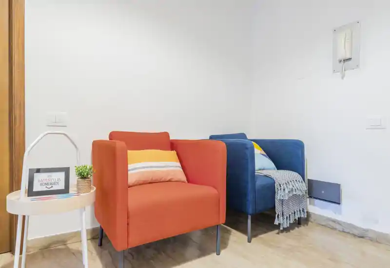 Bright, neatly styled seating area with two colorful armchairs and decorative cushions — a cheerful corner ideal for reading or relaxing.