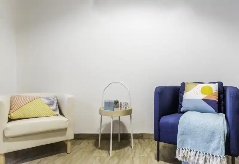 Bright, cozy seating area with two armchairs, decorative cushions and a small side table—ideal for a relaxing corner in a living room.