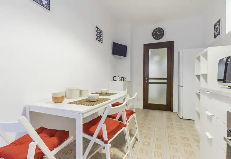 Bright, tidy dining area with a white table, red-cushioned folding chairs and decorative placemats — ideal for casual meals.
