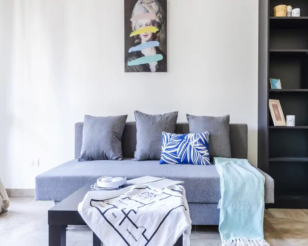 Soggiorno moderno e luminoso con divano grigio, cuscini decorativi e tavolino basso — perfetto per rilassarsi o ricevere ospiti.