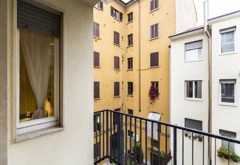 Small urban balcony overlooking the inner courtyard with metal railing and neighboring apartment façades — ideal to show outdoor space in a city rental.