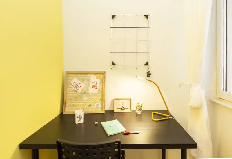 Bright, tidy desk corner with a modern black table, yellow desk lamp and small decorative items — ideal as a compact home office or study nook.