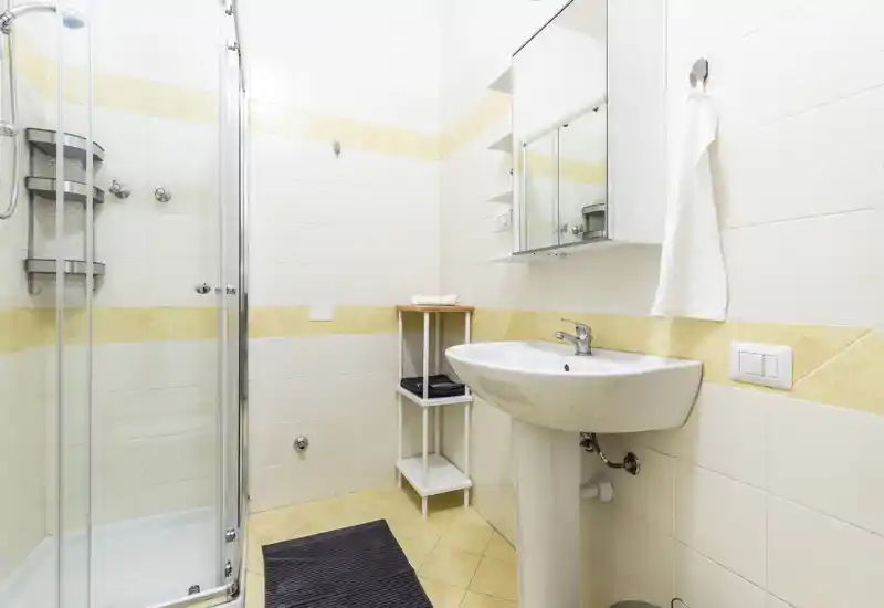 Bright, clean bathroom with a corner glass shower, pedestal sink and mirrored medicine cabinet — ideal for a compact rental unit.