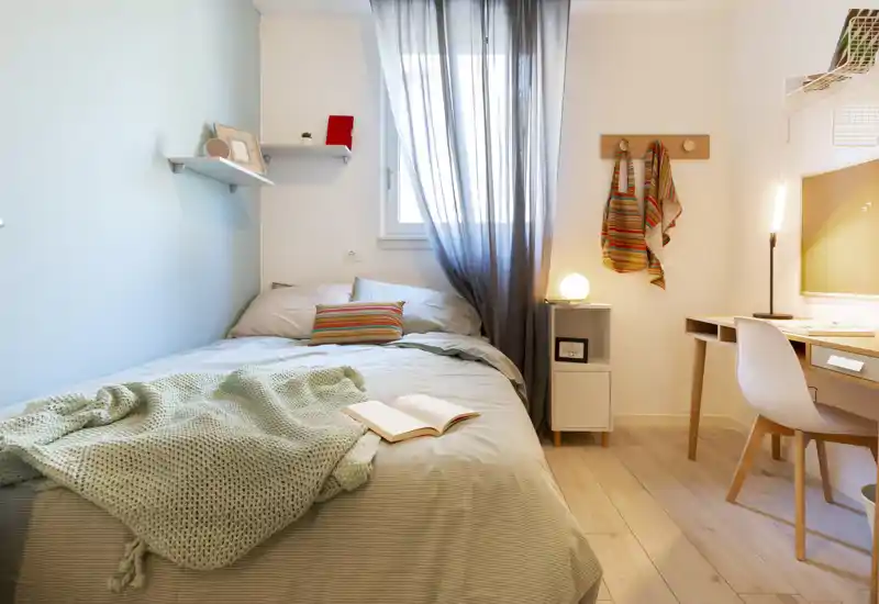 Camera da letto luminosa e ben arredata con un ampio letto, morbida coperta e una scrivania accanto per lavorare comodamente.
