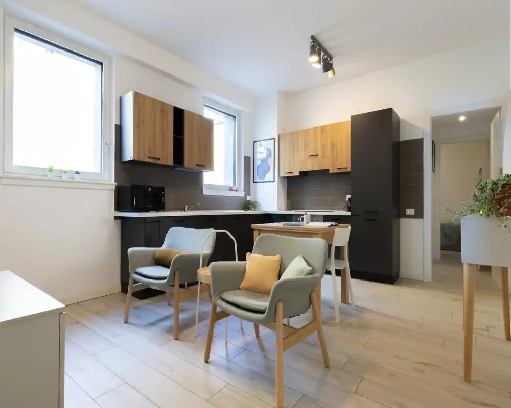 Bright, modern open-plan living area with a compact kitchen and two cozy armchairs — ideal for a small apartment or studio.
