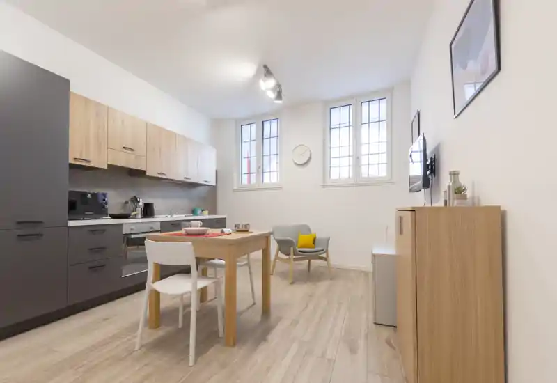 Bright, modern open-plan living area with a compact kitchen, dining table and a cozy armchair — ideal for a city apartment stay.