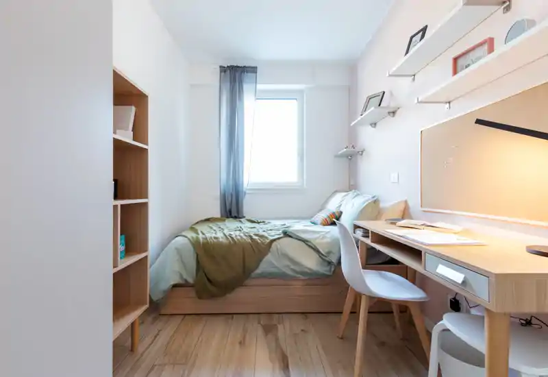Bright, well-staged single bedroom with a neatly made bed, desk workspace and shelving — ideal for students or a solo renter.