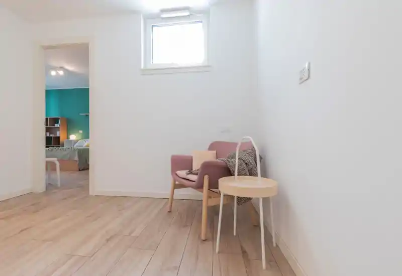 A bright, minimal living corner featuring a comfortable armchair, side table and soft textiles; clean lines and natural light create a calm, inviting space.