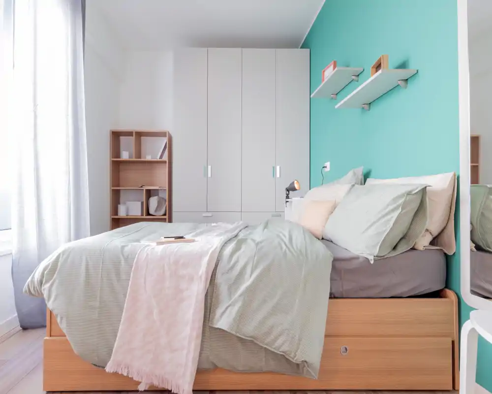 Camera da letto luminosa e moderna con un ampio letto in legno, biancheria morbida e accenti pastello; la luce naturale illumina la stanza e l'armadio a muro offre ampio spazio.