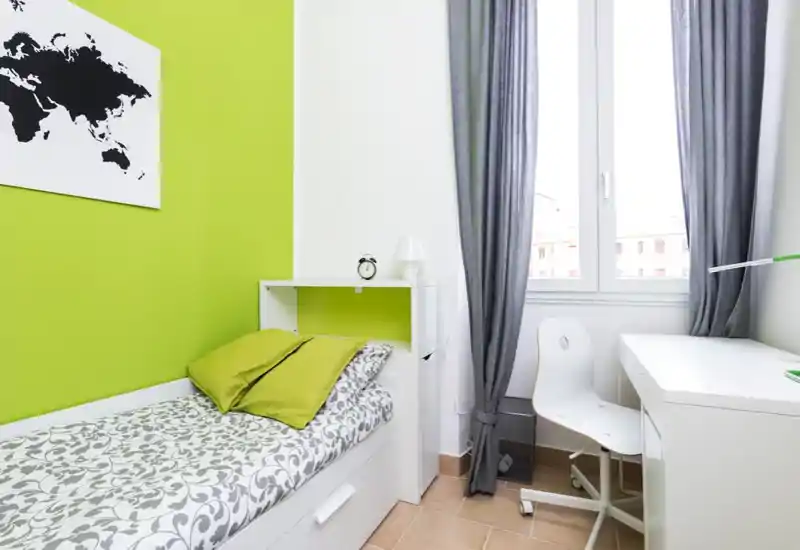 Compact, modern single bedroom with a comfortable bed, bright window and a practical desk — ideal for a student or short-stay rental.