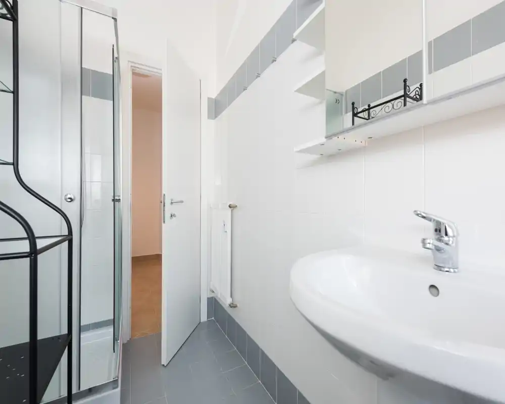Bright, compact bathroom with a sink, mirrored cabinet and a shower cubicle. Neutral tiles and clean lines give a simple, modern look.