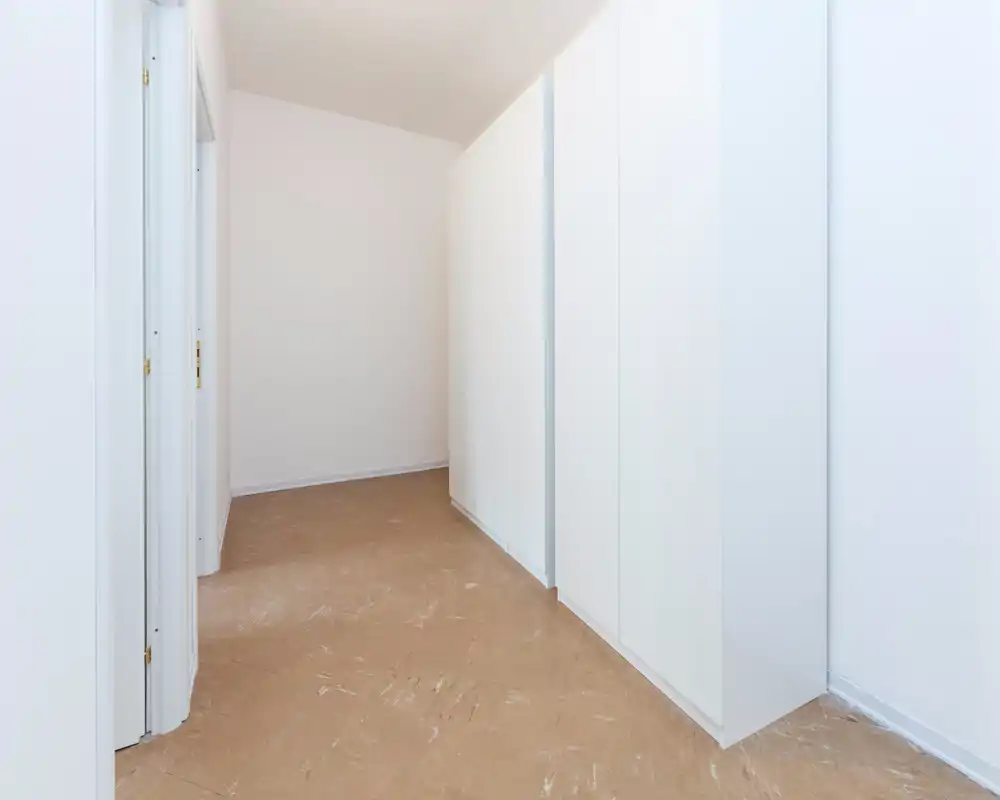 Ingresso/corridoio corto semplice e luminoso con pareti bianche e armadi a muro; pavimento neutro e linee minimaliste.