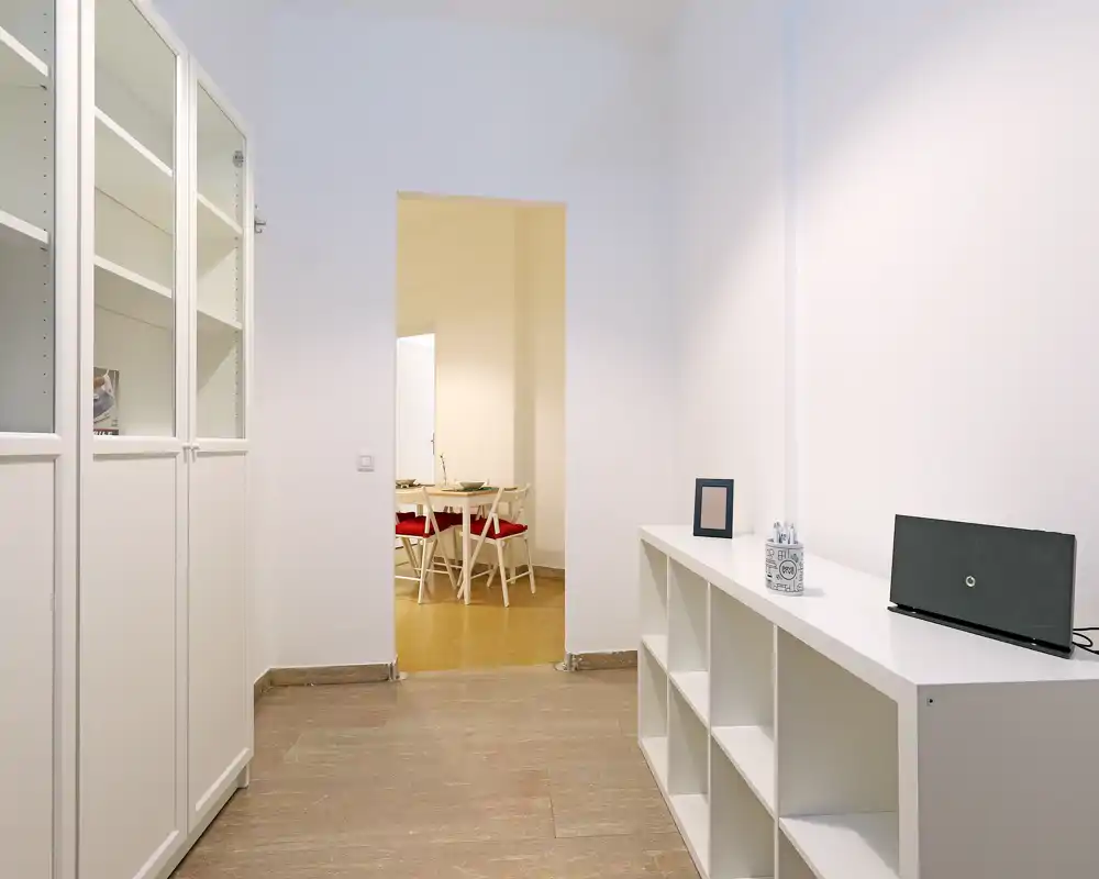 Entrada/pasillo minimalista y luminoso con armarios blancos y vista al comedor; líneas limpias y tonos neutros crean un espacio de paso acogedor.