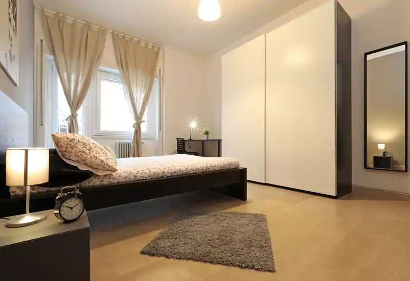 Dormitorio moderno y luminoso con cama baja, textiles suaves y un gran armario — líneas limpias e iluminación cálida que lo hacen acogedor.