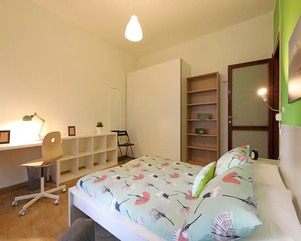 Chambre lumineuse et bien mise en scène avec lit double, bureau et étagères — idéale pour un séjour confortable.
