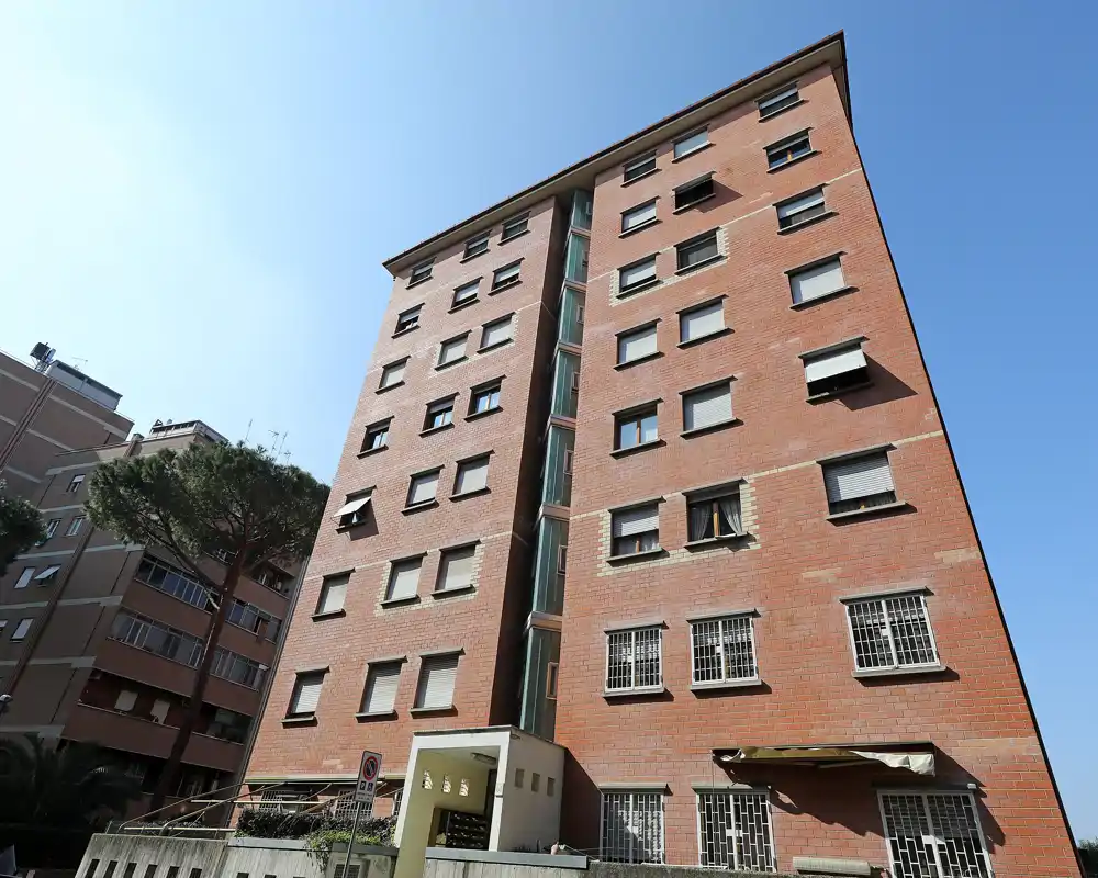 Toma exterior de un edificio residencial de ladrillo desde nivel de calle con luz diurna, adecuada como imagen de la fachada de la propiedad.