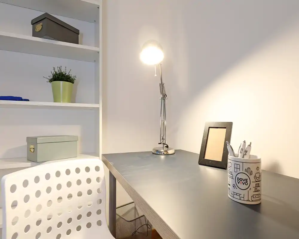 Bright, minimal home office corner with a clean desk, modern lamp and shelving—ideal for focused work or study.