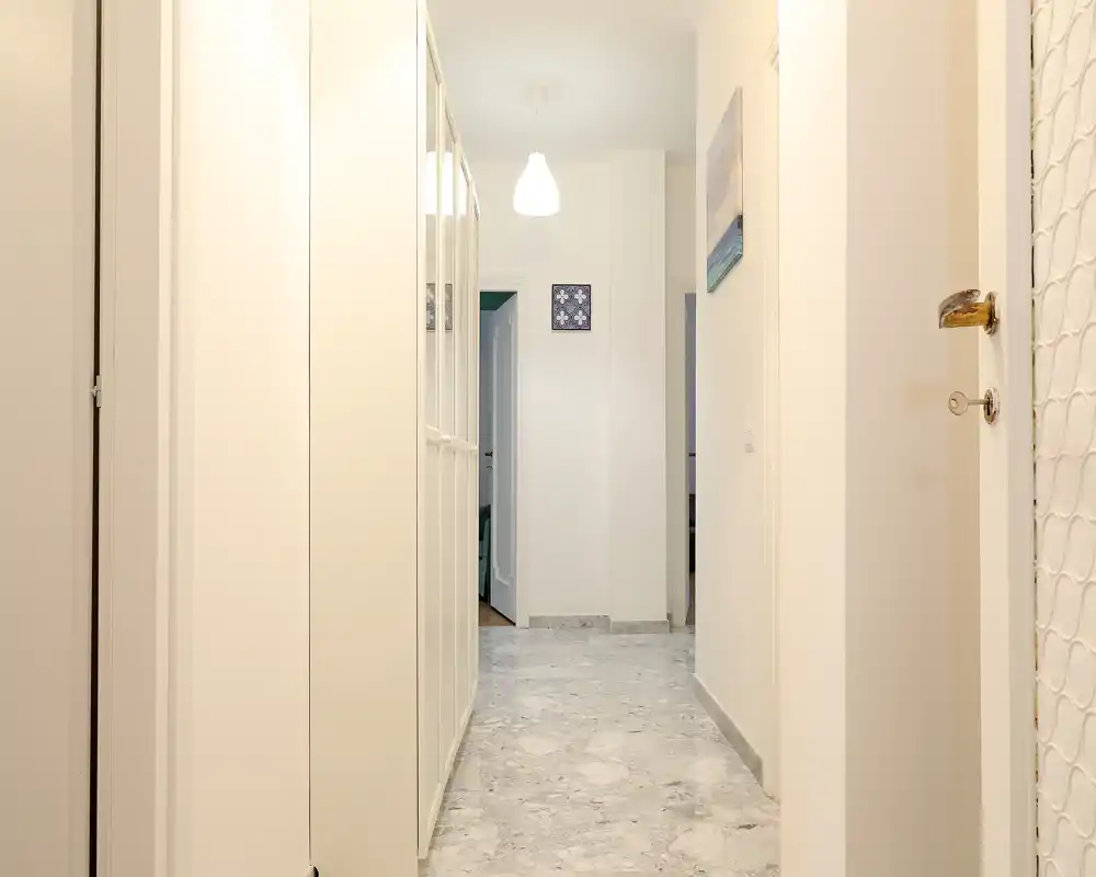 Bright, clean entrance hallway with built-in storage and marble-look flooring, softly lit by a ceiling pendant — ideal first impression for a rental.
