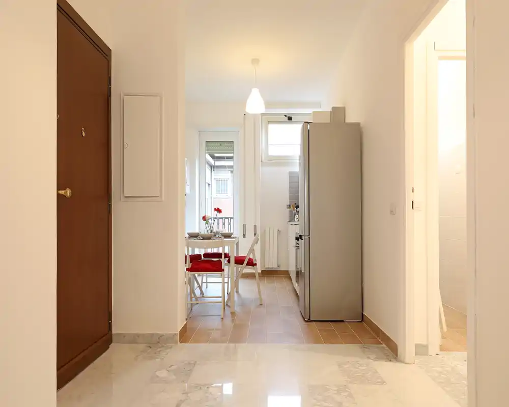 Compact open kitchen with a small dining table and natural light. Ideal for a couple or single occupant, with modern fridge and simple, bright furnishings.