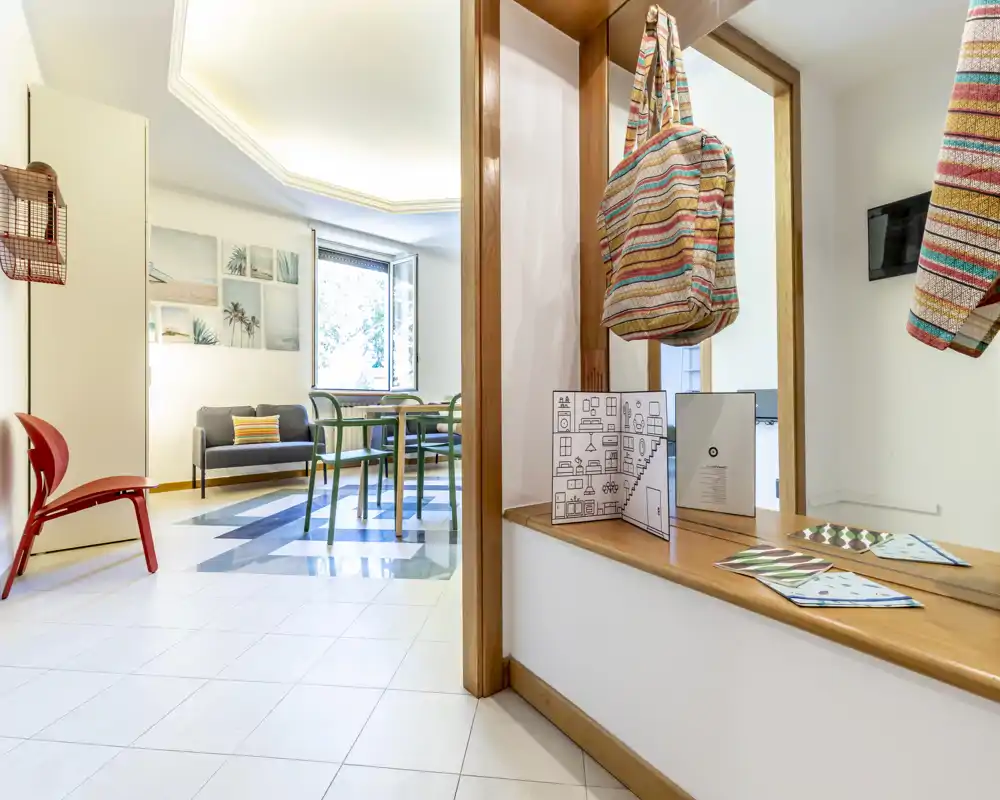 Bright, modern living area with a small sofa, dining table and chairs near a large window; fresh, airy styling ideal for rental photos.