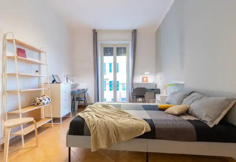 Bright, well-staged bedroom with a large bed, cosy textiles and a desk by the window—ideal for comfortable stays or working from home.