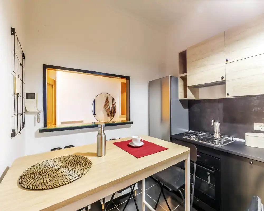 Compact modern kitchen with a breakfast bar, gas cooktop and integrated refrigerator — bright, well-styled for a small apartment.